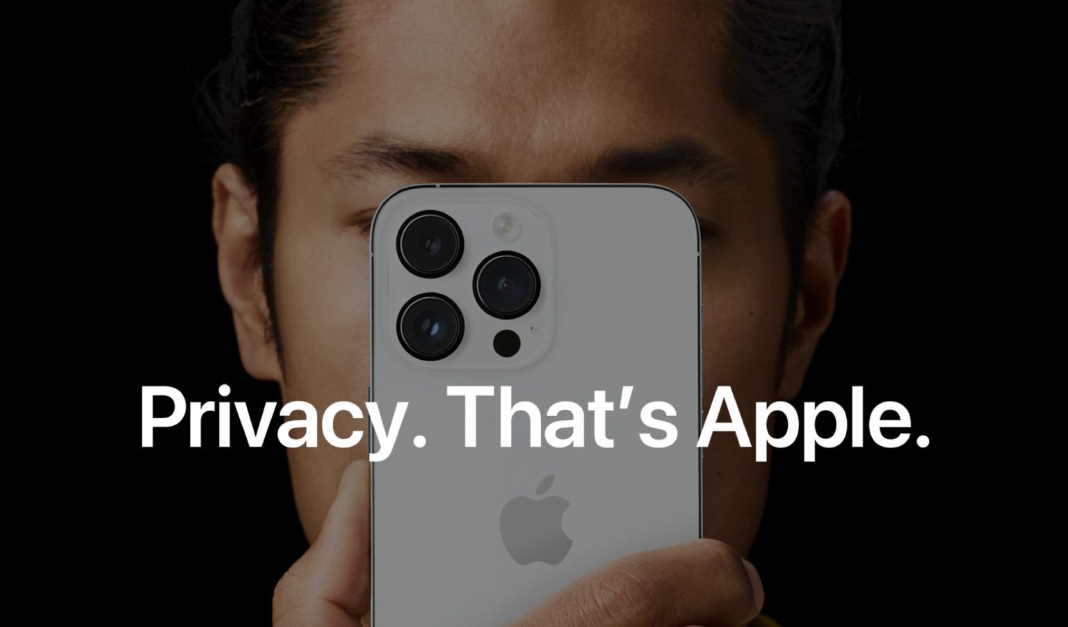 Person holding a white iPhone with triple camera setup close to their face, with the text “Privacy. That’s Apple.” prominently displayed, highlighting Apple’s emphasis on user privacy