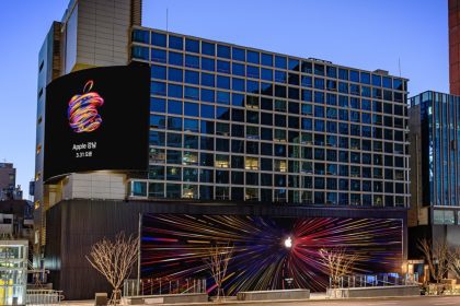 Exterior of the new Apple Store in Gangnam, South Korea, featuring colorful neon Apple logo displays and a large opening announcement billboard on the building facade