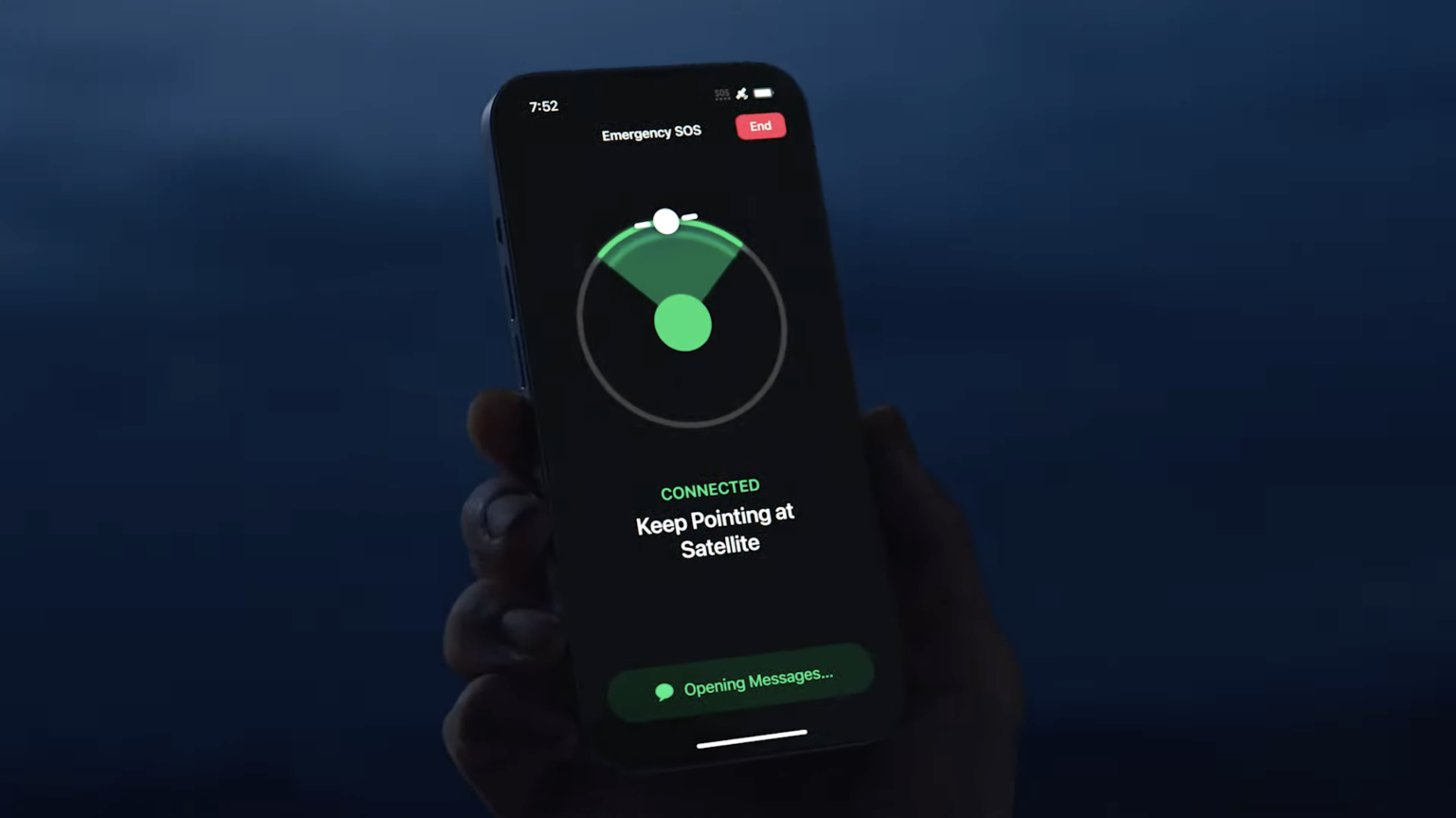 Hand holding an Apple iPhone 14 displaying the Emergency SOS via Satellite feature, showing connection status and instructions to keep pointing at the satellite, against a dark background
