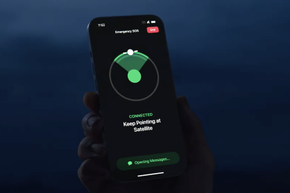 Hand holding an Apple iPhone 14 displaying the Emergency SOS via Satellite feature, showing connection status and instructions to keep pointing at the satellite, against a dark background