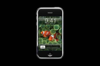 Image of the original iPhone with a black background, featuring the classic ‘slide to unlock’ screen with a clownfish wallpaper