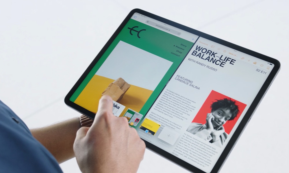 A person interacts with an Apple iPad running iPadOS. The screen displays a split-view with two apps side-by-side. On the left, a website with a green and yellow theme shows an image of a paper bag and some text. On the right, a digital magazine or article titled “WORK-LIFE BALANCE” features a black and white photo of a smiling person with a red background. The person’s hand is tapping on the screen, demonstrating the device’s multitasking capabilities.