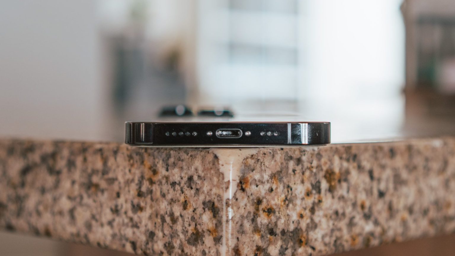 Close-up of an iPhone resting on a countertop, showcasing the device’s charging port and speaker grills