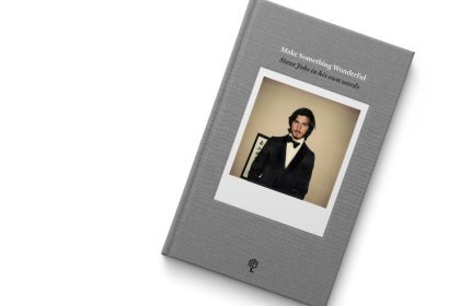 Grey fabric book cover on a white backgroud bearing the words "Make Something Wonderful, Steve Jobs in his own words" with a polaroid photograph of Steve Jobs in a suit and bow tie in his mid twenties