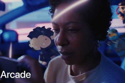 The image is a still from an Apple Arcade advertisement. It features a person intensely focused on playing a game on their mobile device. Animated gaming characters float around them, blending the real and virtual worlds. The background shows the interior of a car with a blurred cityscape outside the windows, giving a sense of immersion in the gaming experience. The Apple Arcade logo is prominently displayed in the bottom left corner.